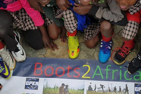 Children posing with football boots donated through the Boots2Africa Campaign.