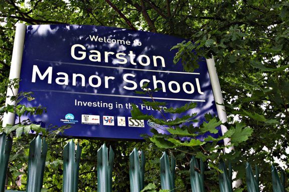 A blue sign for Garston Manor School.