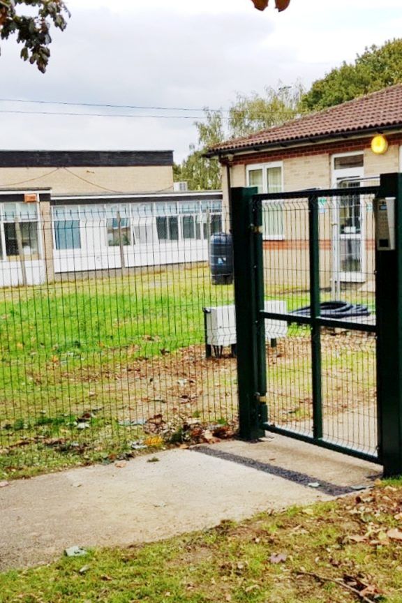 A green security gate outside a school.