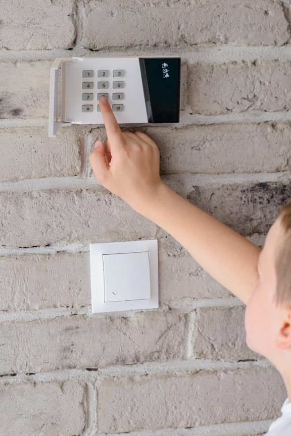 A young boy setting the home alarm system.