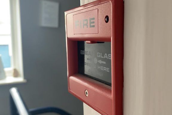 A red fire alarm break glass unit on the wall.