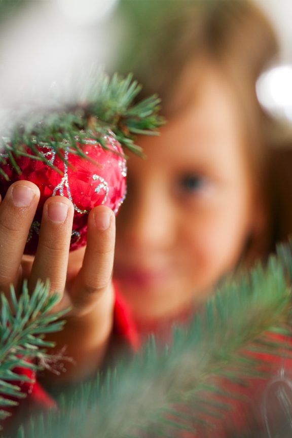 A child placing a red bauble on a Christmas tree helping to illustrate Amthal's latest news on Christmas security.