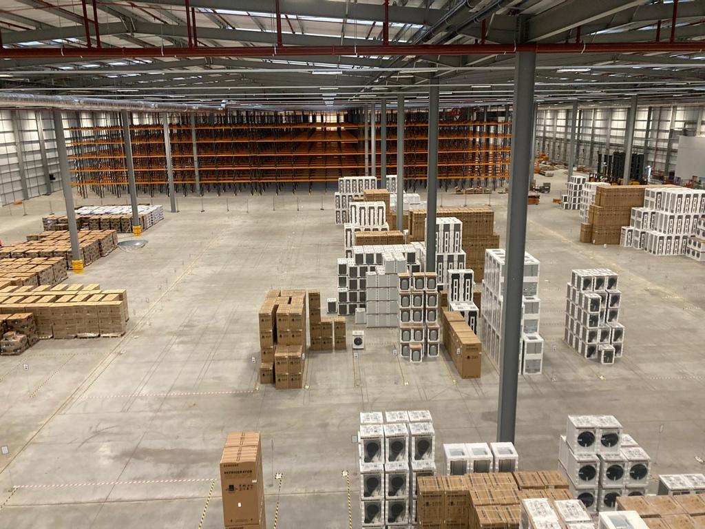 Pallets and various pieces of equipment stacked inside a large warehouse.