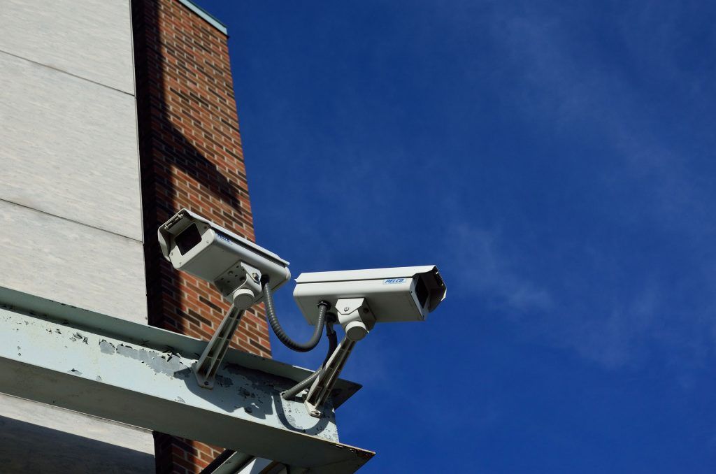 Two security cameras on the side of a commercial building to help illustrate Amthal's business security systems.