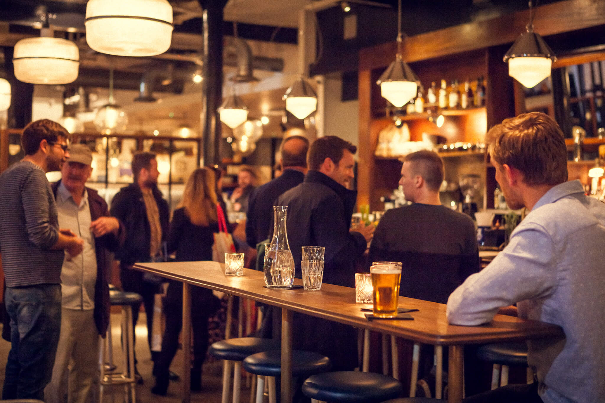 Drinkers in a busy pub socialising.
