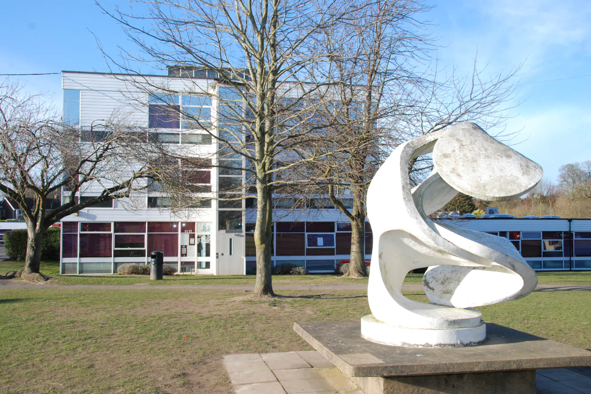 A more modern (1960s) school building with a modern white sculpture on display in the foreground.