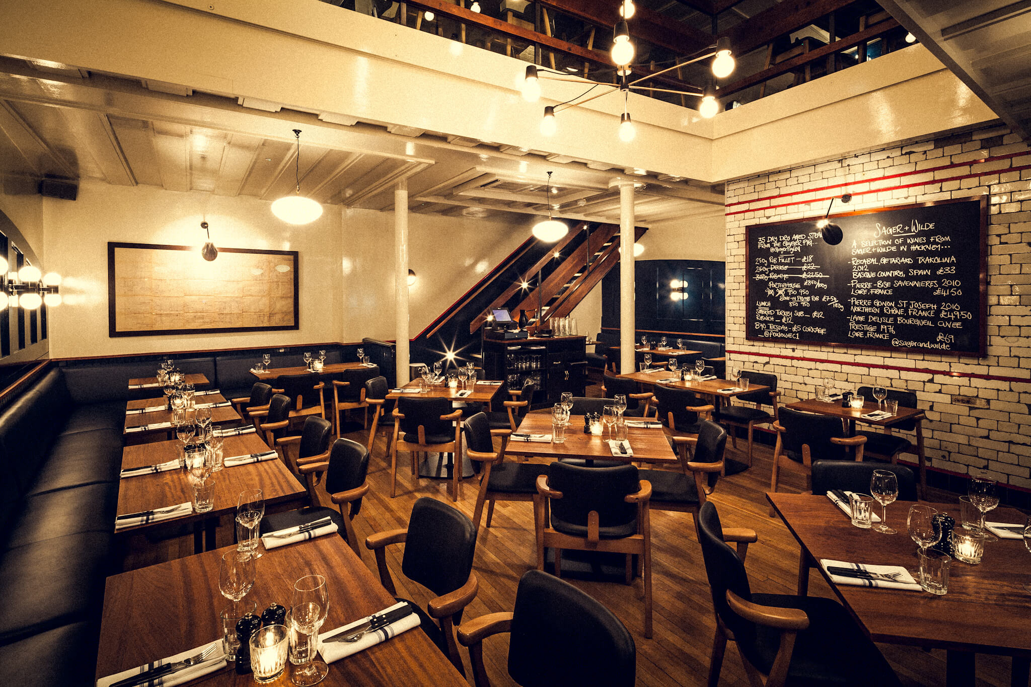 An empty pub with tables and chairs for dining with a mezzanine floor.