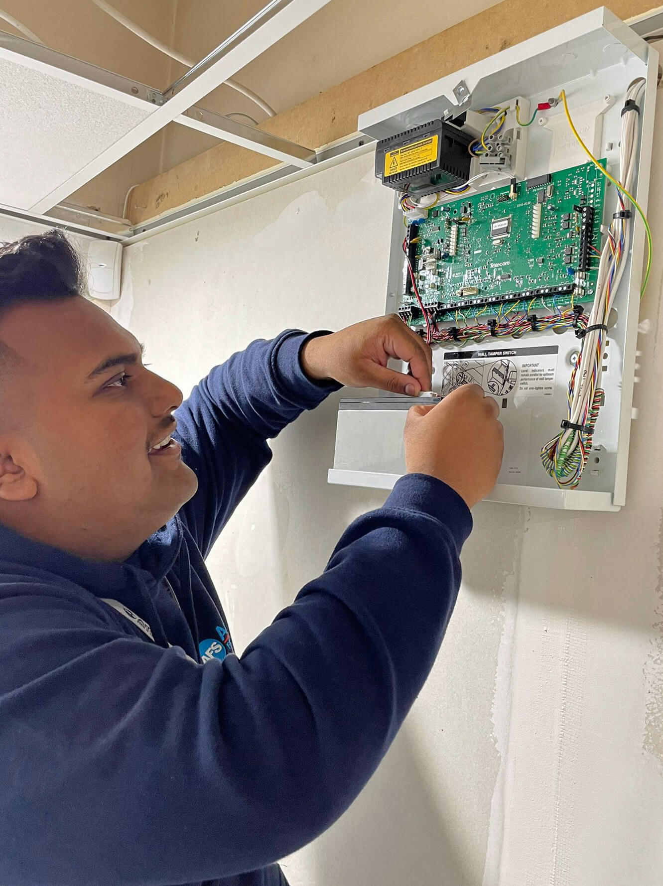 An Amthal technician working on a circuit board that's part of a fire or security system.