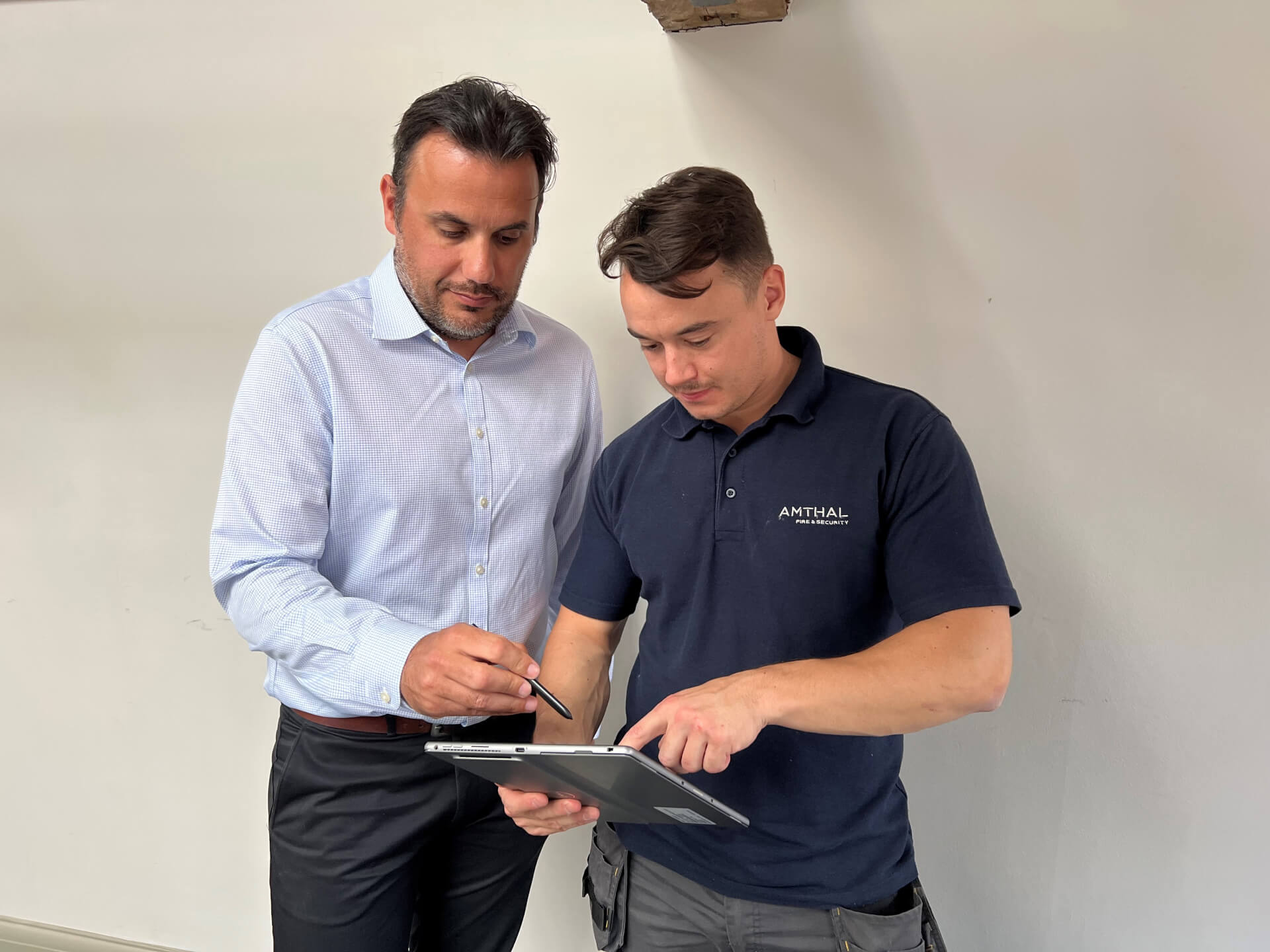 Two Amthal employees conferring over a tablet.